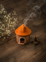 Haus aus Giesspulver mit orangem Dach und aus dem Kamin steigendem Rauch